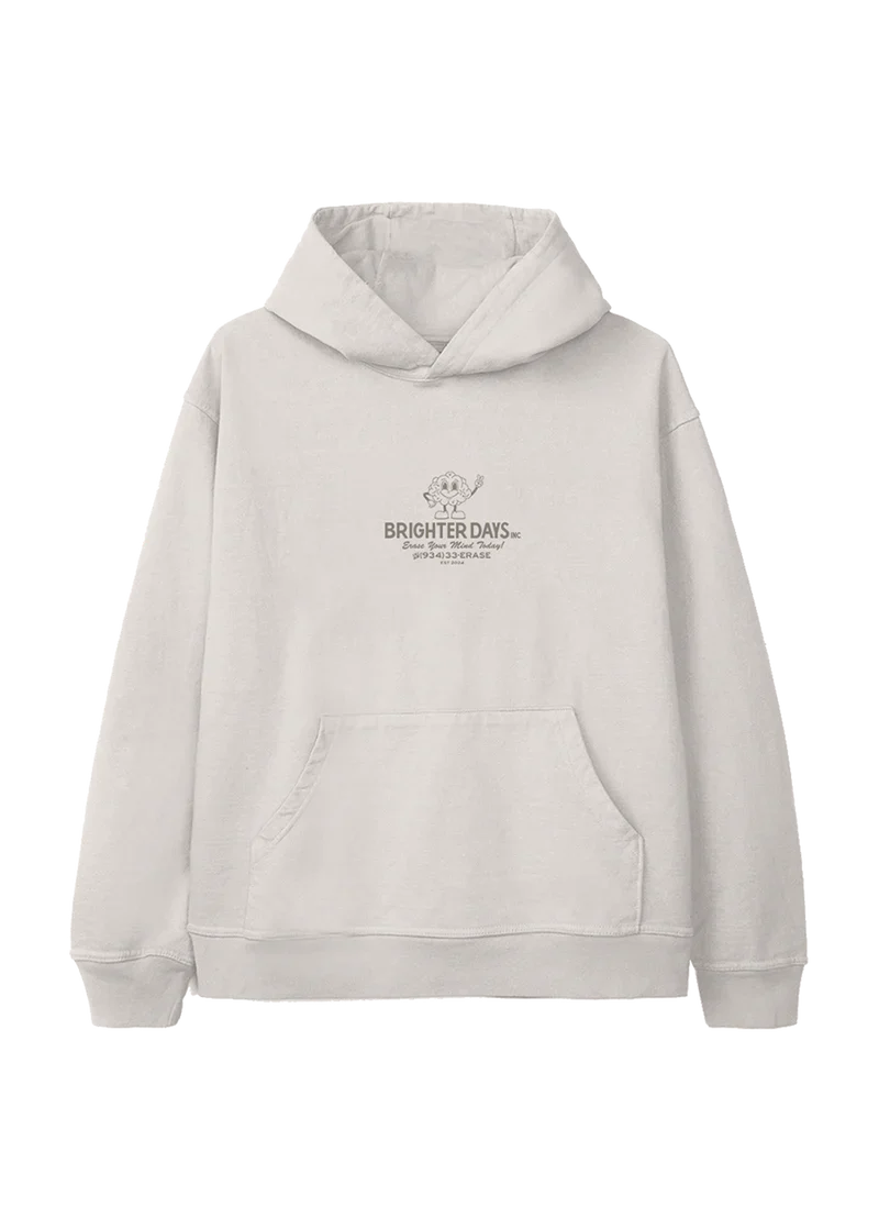 Off-white hoodie with a small retro cartoon flower mascot above the text "Brighter Days Inc." and the phrase "Erase Your Mind Today!" followed by a phone number, "(934) 33-ERASE" — playful, nostalgic merch from Ariana Grande’s eternal sunshine collection.