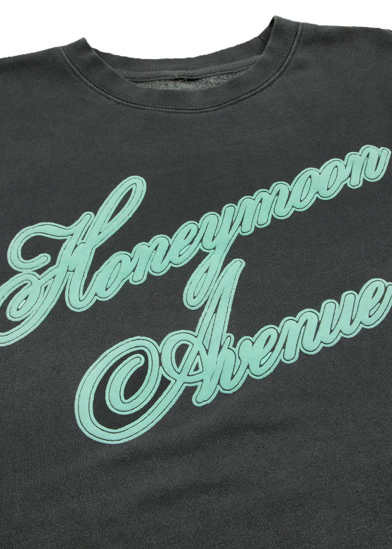 Zoomed-in view of mint green 'Honeymoon Avenue' embroidery on soft black fabric. The stitching pops with vintage flair, capturing the aesthetic of Ariana Grande’s debut album era.