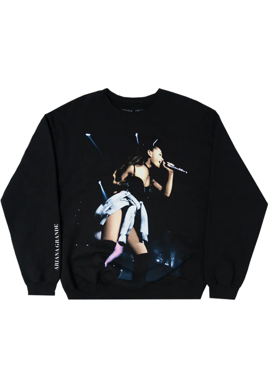 Black Ariana Grande crewneck sweatshirt featuring a full-color concert photo from the My Everything tour, showing Ariana mid-performance in cat ears and thigh-high boots, with "Ariana Grande" printed vertically on the sleeve.