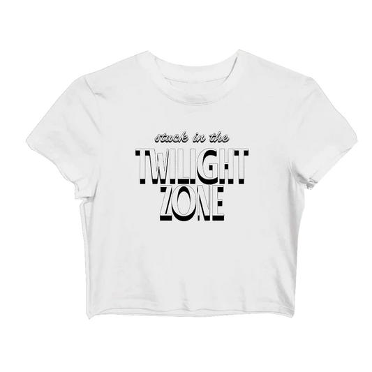 White Ariana Grande baby tee with bold black-and-white retro text that says “stuck in the TWILIGHT ZONE” across the front — cropped fit from the official Twilight Zone merch line.