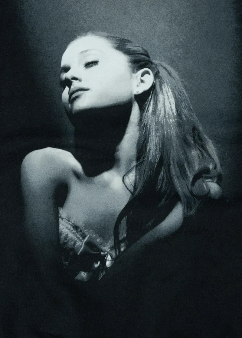 Close-up black-and-white image of Ariana Grande with her head tilted back, wearing a corset top, under dramatic lighting. A stylized shot reminiscent of the Yours Truly album cover.