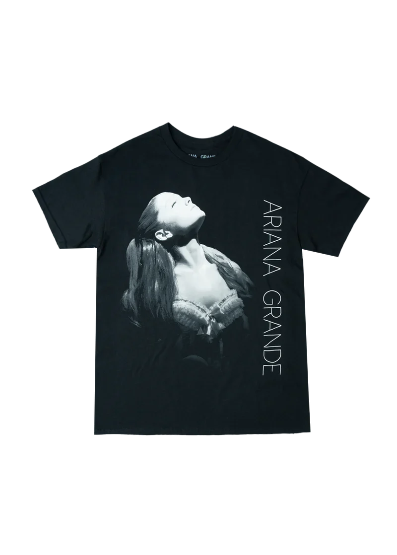 Black Ariana Grande t-shirt featuring a grayscale portrait of Ariana in a spotlight, wearing a lace corset top, with 'ARIANA GRANDE' printed vertically along the side. A bold graphic tee from the Yours Truly 10th Anniversary collection.