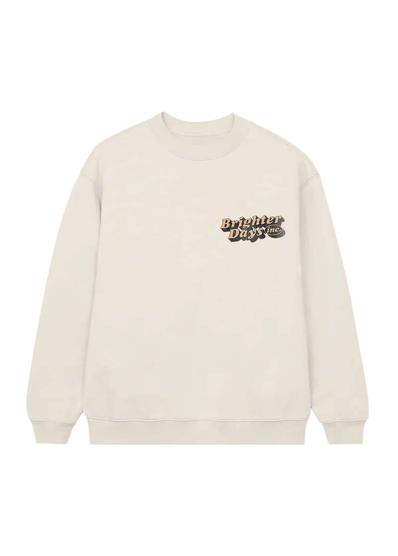 Cream crewneck sweatshirt with a small retro-style “Brighter Days Inc.” logo printed on the left chest in bold orange and black lettering — cozy and vintage-inspired merch from Ariana Grande’s collection.