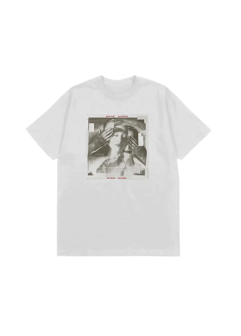 White t-shirt featuring a fragmented grayscale collage of Ariana Grande's face being covered by gloved hands, with red text reading "eternal sunshine" and "ariana grande" above and below the image — official merch from her eternal sunshine album.