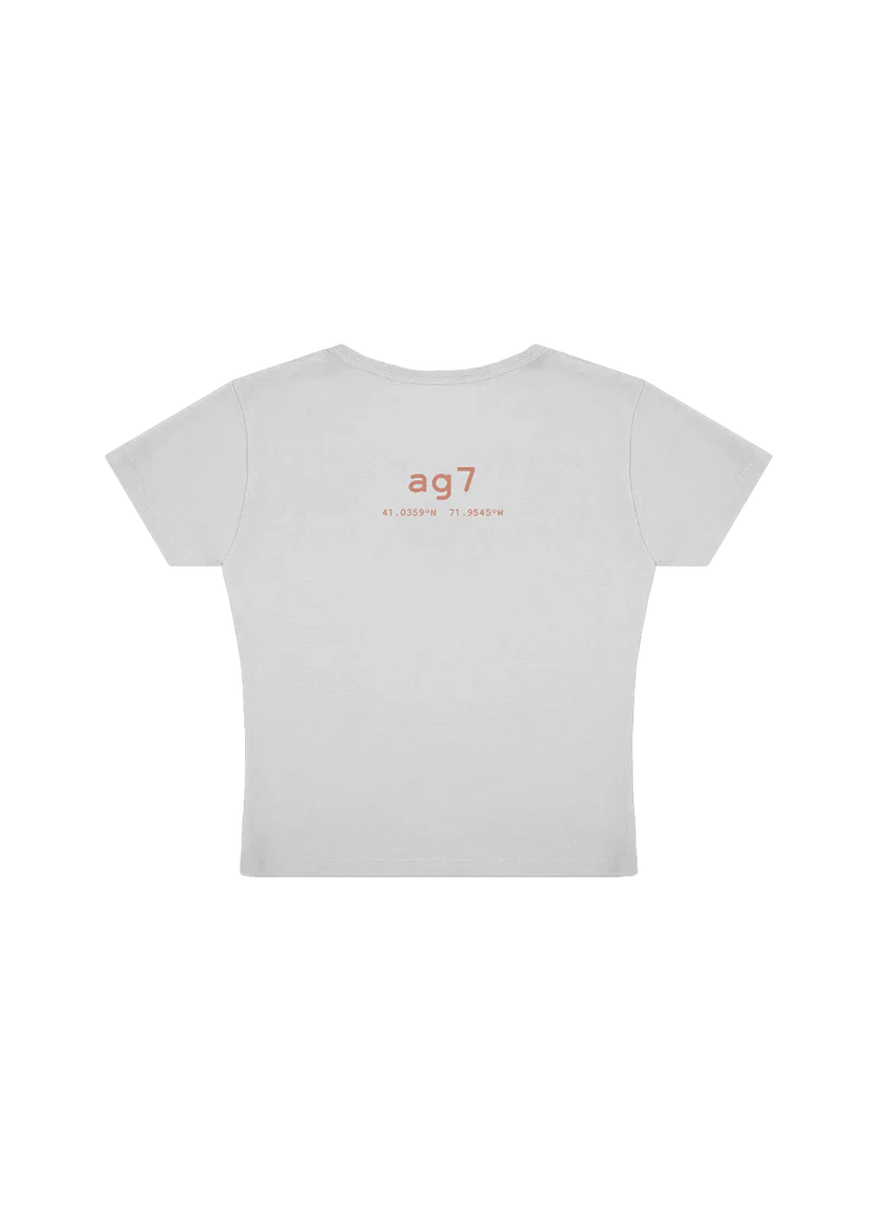 Back of white cropped tee with “ag7” printed in soft coral text, followed by geographic coordinates: 41.0359°N, 71.9545°W. A subtle nod to Ariana Grande’s 7th studio album, with a clean and modern look.


