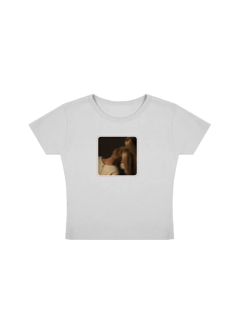 White cropped Ariana Grande t-shirt featuring a centered square photo of two women leaning in close, bathed in warm lighting. A minimal, intimate design celebrating the emotional tone of the eternal sunshine era.

