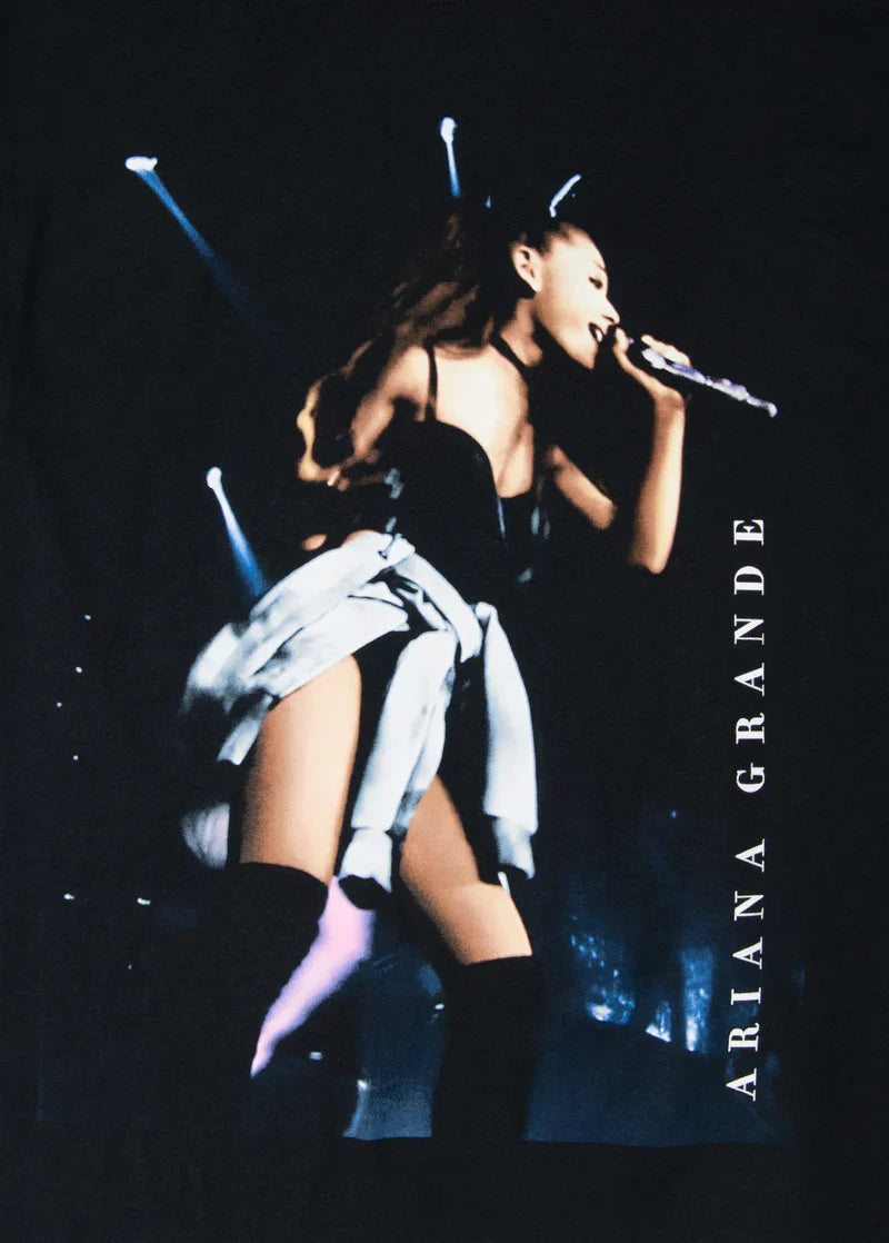 Close-up of the Ariana Grande My Everything live photo tee showing detailed stage lighting, Ariana’s dynamic pose with microphone, and vertical “Ariana Grande” text along the edge.


