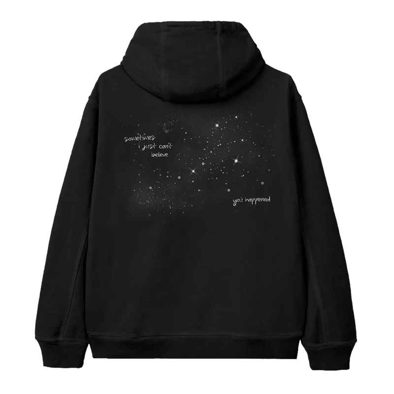 Back of Ariana Grande’s black Twilight Zone hoodie with a galaxy-style constellation graphic and handwritten lyrics that read, “sometimes i just can’t believe you happened.”

