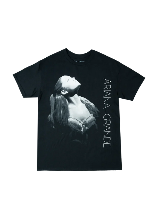 Black Ariana Grande t-shirt featuring a grayscale portrait of Ariana in a spotlight, wearing a lace corset top, with 'ARIANA GRANDE' printed vertically along the side. A bold graphic tee from the Yours Truly 10th Anniversary collection.