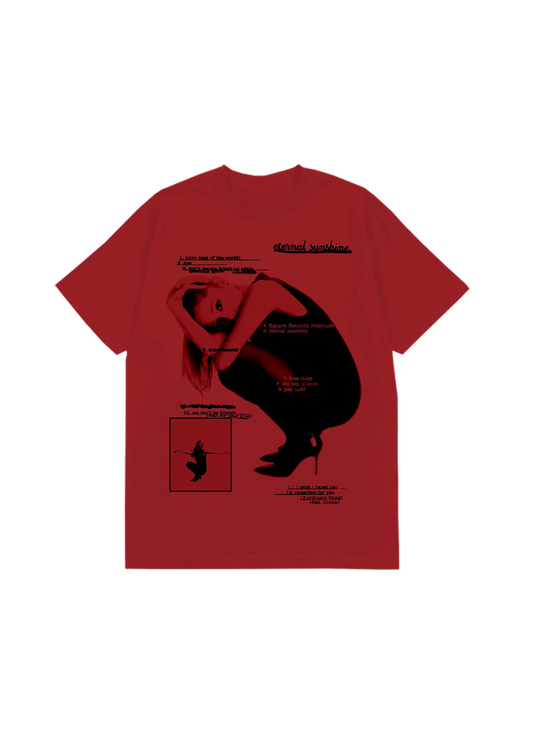 Bright red Ariana Grande t-shirt showcasing a black-and-white photo of Ariana in a crouched pose, overlaid with the complete Eternal Sunshine tracklist in black text. Includes song titles like “eternal sunshine,” “we can’t be friends,” and “ordinary things (feat. nonna),” styled in a raw, editorial layout.

