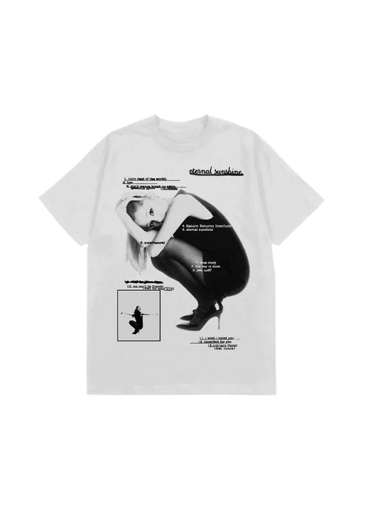 White Ariana Grande t-shirt featuring a black-and-white photo of Ariana crouched in heels, overlaid with the full Eternal Sunshine album tracklist. Includes titles like "intro (end of the world)", "eternal sunshine", "we can't be friends", and "ordinary things (feat. nonna)" in stylized text.

