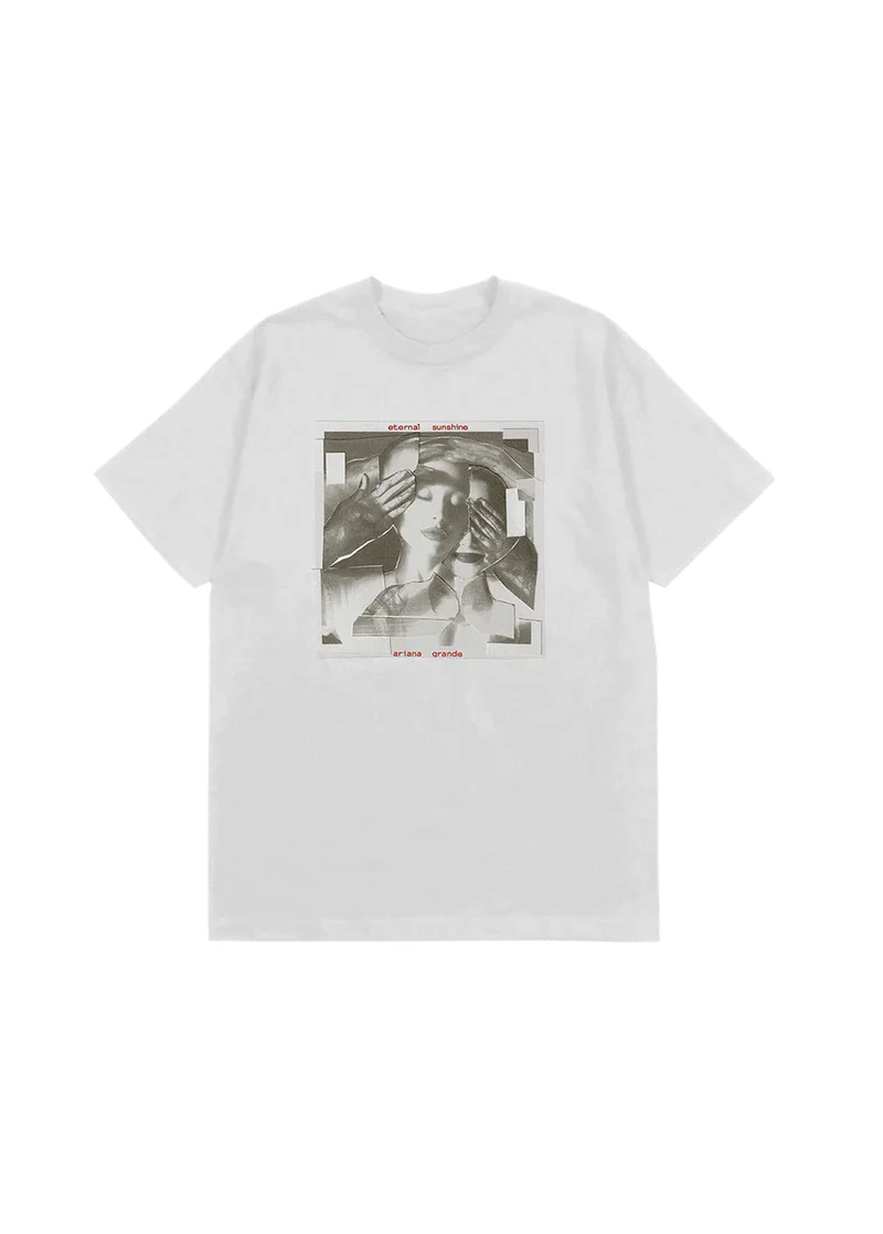 White t-shirt featuring a fragmented grayscale collage of Ariana Grande's face being covered by gloved hands, with red text reading "eternal sunshine" and "ariana grande" above and below the image — official merch from her eternal sunshine album.

