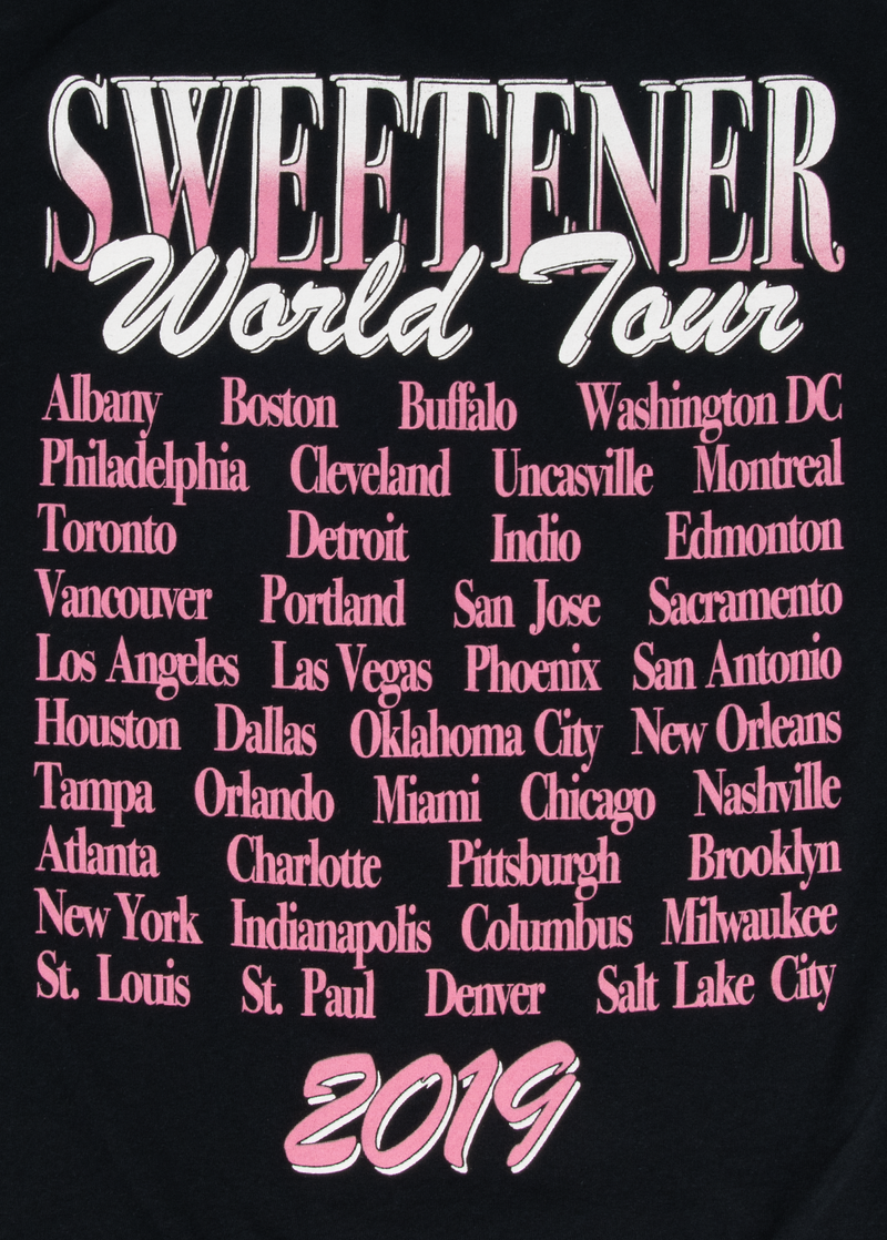 Close-up of the Sweetener World Tour 2019 back print on black Ariana Grande t-shirt, showing a full list of cities in pink text beneath the large tour title. A detailed look at the cities visited during her iconic 2019 tour.


