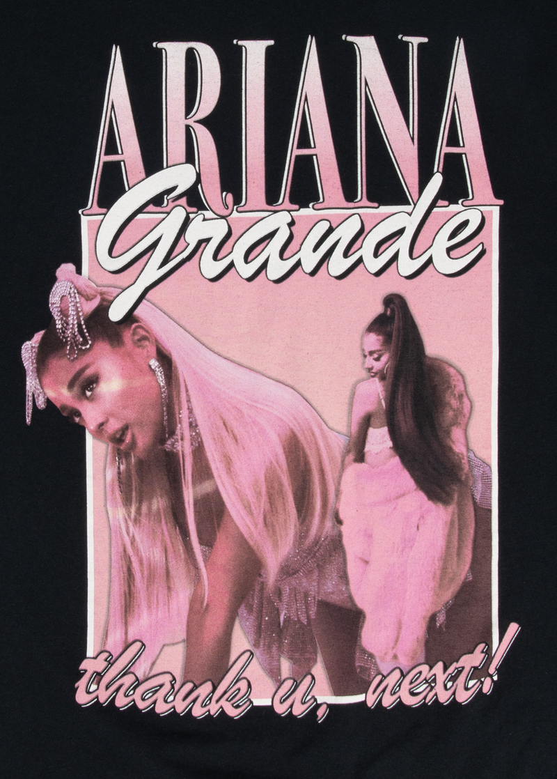Close-up of the pink and white “thank u, next!” graphic on a black Ariana Grande t-shirt, showing Ariana in two poses with long platinum hair and Y2K-inspired outfits. The design includes bold "Ariana Grande" lettering across the top.

